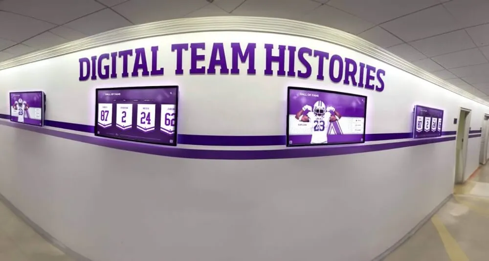 Hallway featuring multiple purple digital screens showing team histories Comprehensive campus recognition display