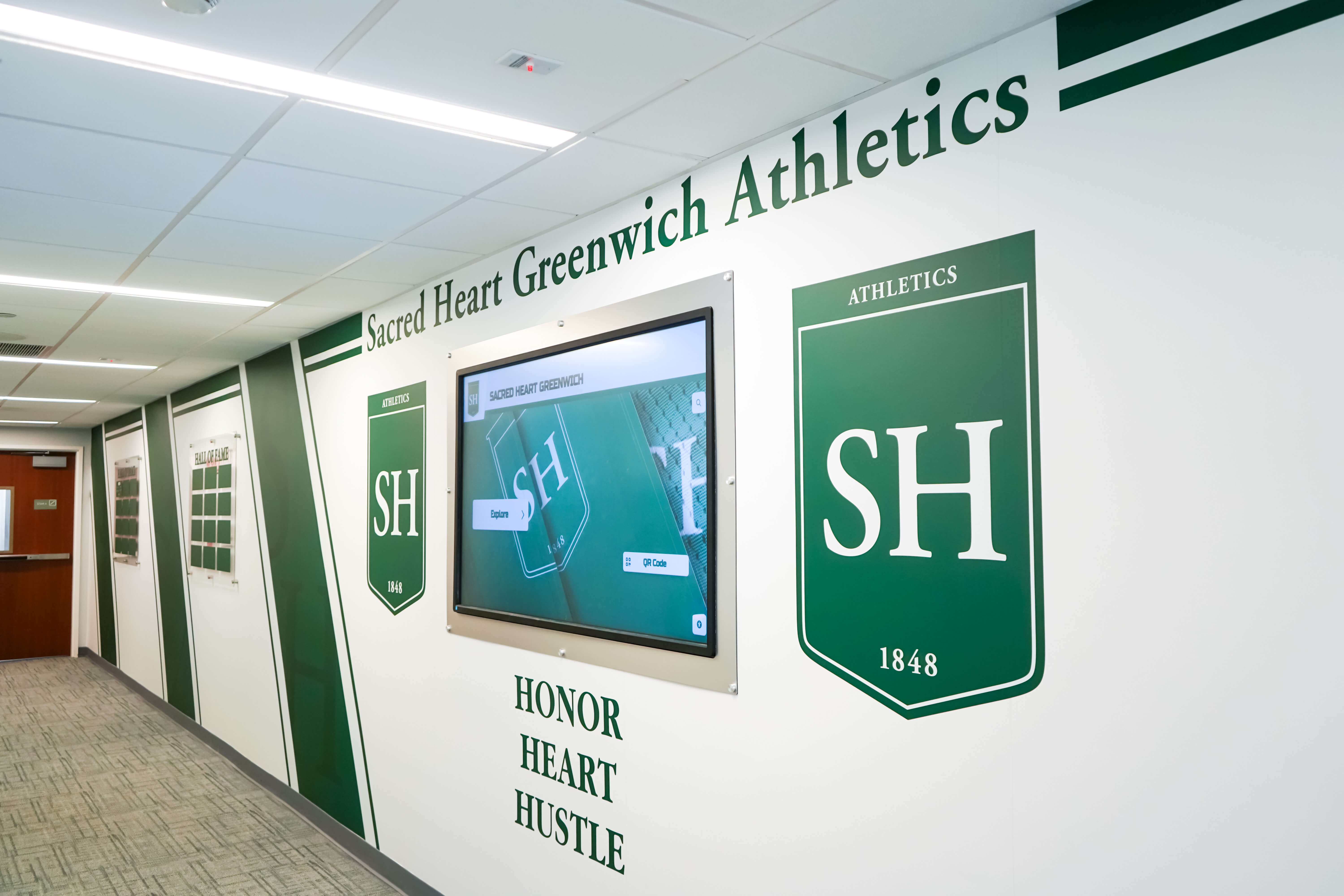 Athletic hallway with trophy cases and digital displays