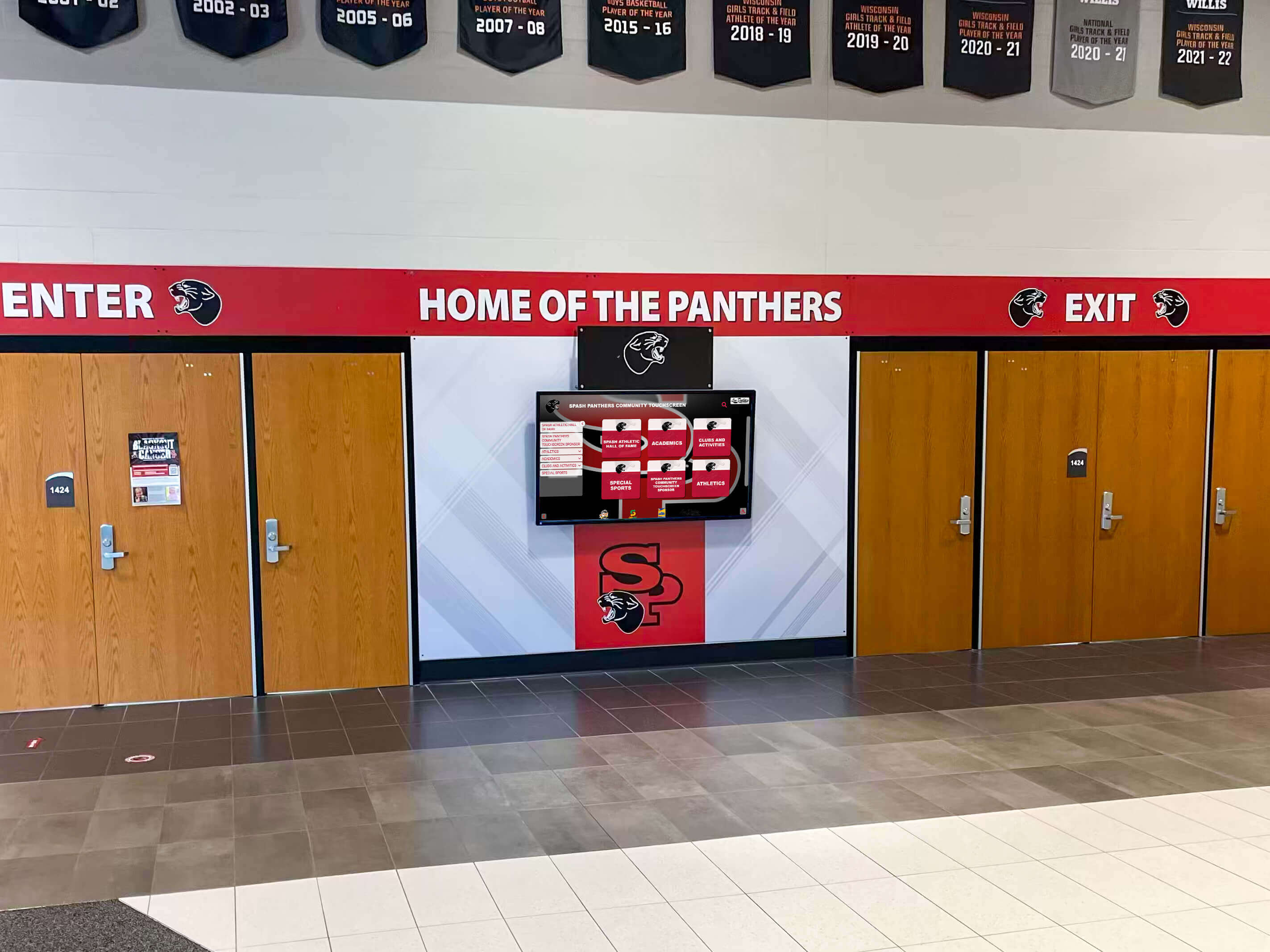 School entrance featuring digital recognition display integrated with traditional Panthers athletics branding School hallway with Home of the Panthers display and digital screen